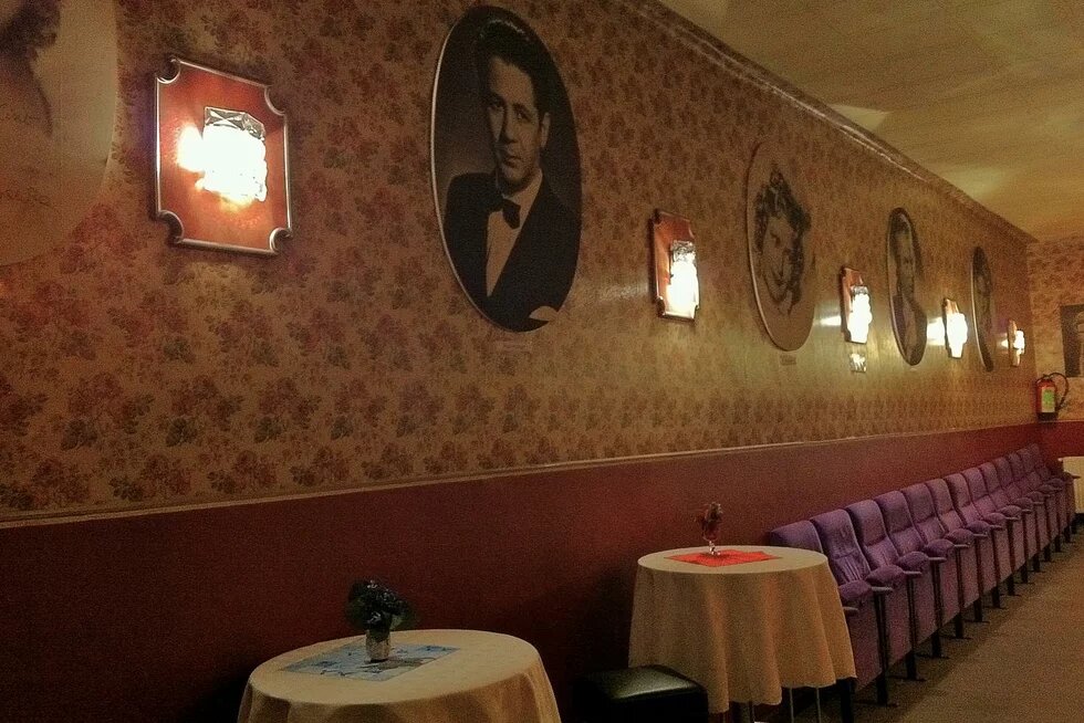 Historisches Foto vom Foyer des Bellaria Kinos in Wien mit kleinen Bistrottischen und verzierter Tapete