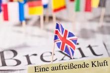 Kleine europäische Länderfahnen, in der Mitte die EU Fahne und vorne die Flagge Großbritanniens. Darunter steht "Brexit. Eine aufreißende Kluft"