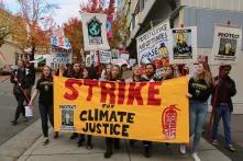 Foto von einem Klimastreik in den USA. Man sieht ca. 30 junge Menschen auf der Straße mit Schildern und einem Banner, auf dem steht: Strike for Climate justice