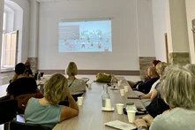 Die Reisegruppe sitzt in einem Seminarraum und schaut eine Powerpoint Präsentation an