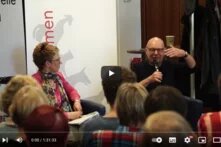 Screenshot vom Mitschnitt der Diskussionsveranstaltung, es sind die Moderatorin und der Gast auf der Bühne sitzend zu sehen