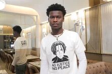 Suraj Mailitafi in einem Café in Berlin-Kreuzberg, auf seinem T-Shirt ist ein Bild von Lorenz A. zu sehen.