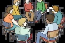 Eine Gruppe von Menschen sitzt in einem Stuhl-Kreis und diskutiert miteinander.