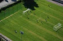 Fußballfeld aus der Vogelperspektive fotografiert. 9 Spieler befinden sich auf dem Feld.