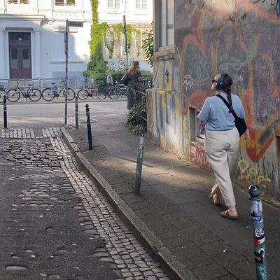 Person läuft durch Straße mit Kopfhörern auf den Ohren, schaut die Straße entlang.